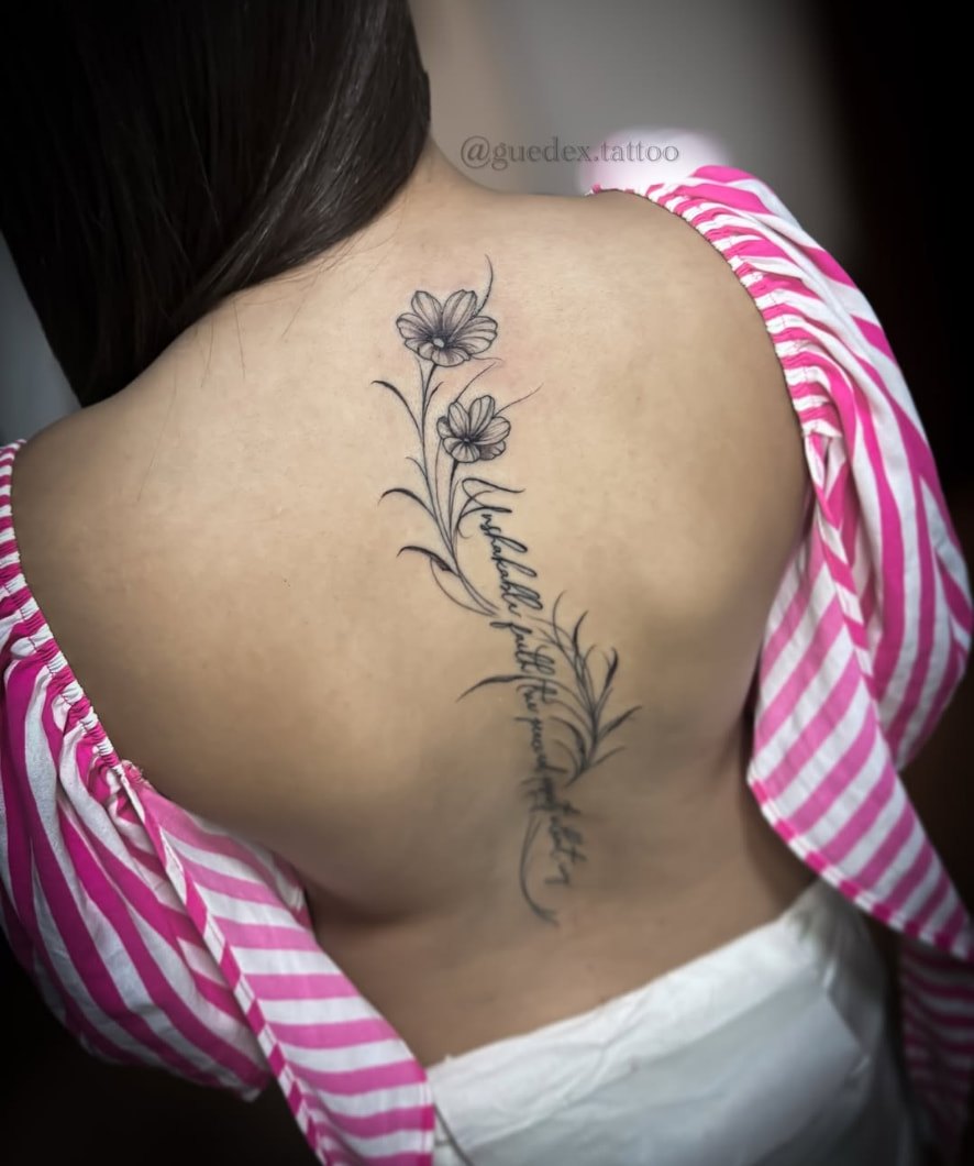Tatuagem de flores e escrita na coluna